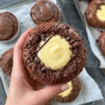 יד מחזיקה מאפה בריוש שוקולד אוורירי במילוי קרם פטיסייר עשיר וציפוי קראמבל, שחזור ביתי למתכון הוויראלי של 'קפה סטף' ירושלים.